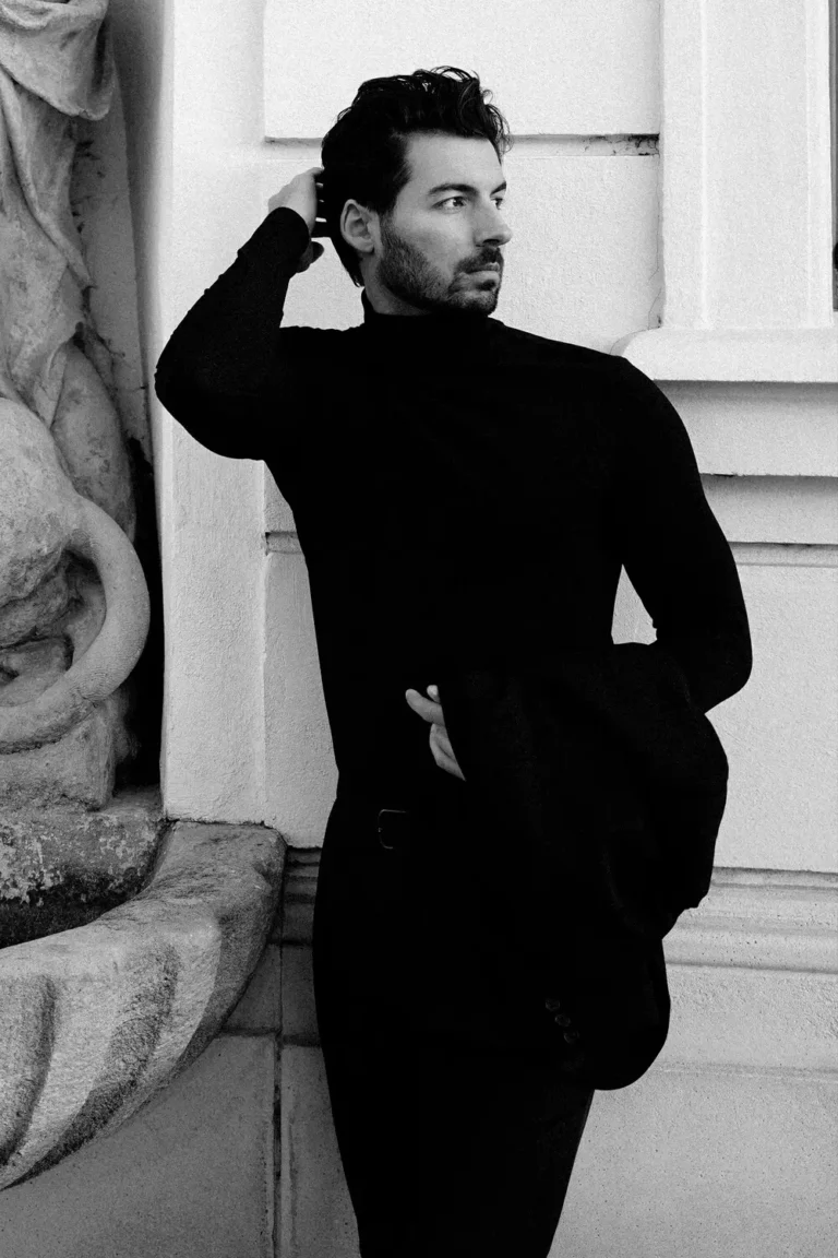 Black-and-white full-body shot of a male model standing in a classic pose